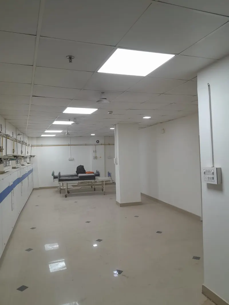 Hospital bay with bed-head units, tiled floor and ceiling lighting